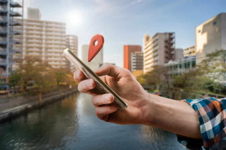 Référencement local en Aveyron : la clé de la réussite ! 1 Main tenant smartphone avec icône localisation, illustrant le référencement local en Aveyron