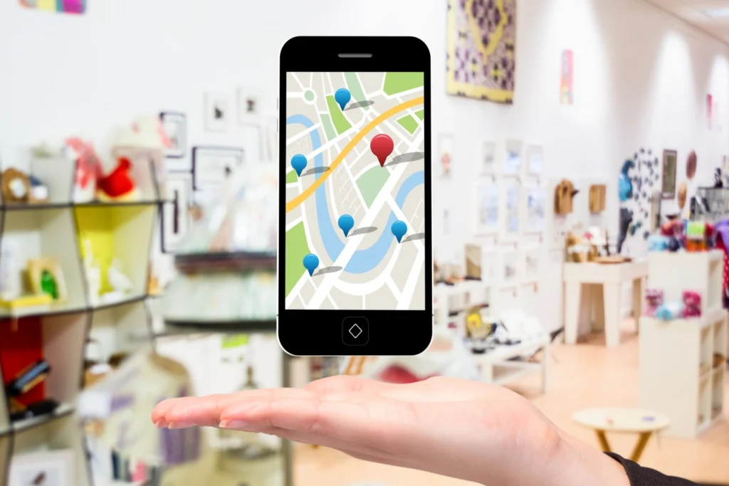 Référencement local en Aveyron : la clé de la réussite ! 2 Main présentant un smartphone affichant une carte avec des marqueurs, illustrant le référencement local